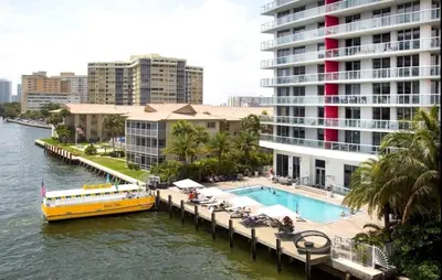 a yellow boat on a river next to a large building at Charming 2 Bedroom Apt with Pool & Beach Service 2808 in Hallandale Beach
