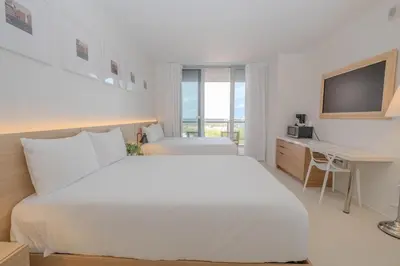 a white bedroom with a large bed and a desk at Luxury Miami Apartment Beach and Poolside drinks 2308 in Hallandale Beach