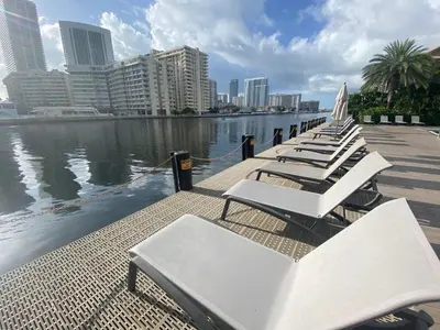 a row of white lounge chairs next to the water at 2b 1b Hallandale Beach Studio with heated Pool 2610 in Hallandale Beach