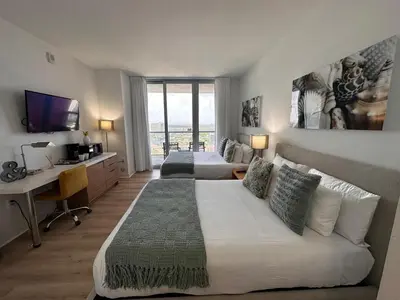 a bedroom with two beds and a desk with a computer at Studio Miami with Beach and Lounge Chairs 2 Full beds 2403 in Hallandale Beach