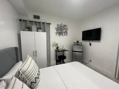 a white bedroom with a bed and a tv at Guest Suite w free parking at 7 min to Miami international airport in Miami