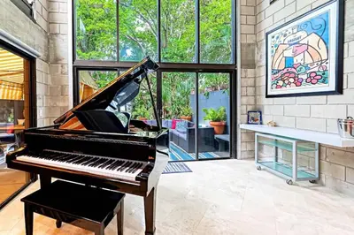 a piano in a room with a wall of windows at Piano House on the Water in Fort Lauderdale