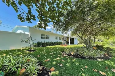 a white house with a yard with plants at Chic 3BR 2BA Getaway with Private Pool Oasis in Fort Lauderdale