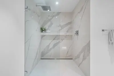 a bathroom with white marble walls and a shower at 1 Bedroom Private Residence at Roney Palace - 607 in Miami Beach