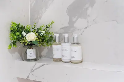 three bottles of essential oils sitting on a shelf in a bathroom at 2 Bedroom Private Residence at Roney Palace -6072B in Miami Beach