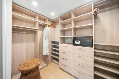 a walk in closet with wooden cabinets and a stool at 1 Bedroom Plus Den Private Residence at Roney Palace -608 in Miami Beach
