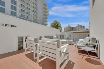 a balcony with white chairs and tables on a building at Eden Collection Studio Steps to Beach in Fort Lauderdale