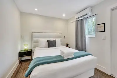 a white bedroom with a large bed and a window at Eden Escape Walk to FLT Beach 2107 in Fort Lauderdale