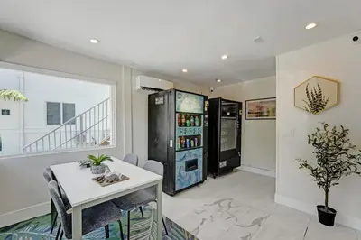a living room with a white table and a refrigerator at Eden Escape Walk to FLT Beach 2101 in Fort Lauderdale