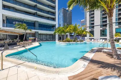 a large swimming pool with palm trees and buildings at Deluxe 2 bed with Amazing views in Miami