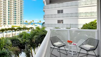 a balcony with two chairs and a table and a building at Beach Club - Oceanfront Luxury, Resort Amenities, Balcony Views in Fort Lauderdale
