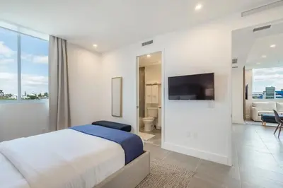 a white bedroom with a bed and a tv on a wall at 2Q Moderno em South Beach | Praia a 5 Min in Miami Beach