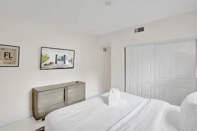 a white bedroom with a white bed and a door at Villa Monaco in Miami Beach