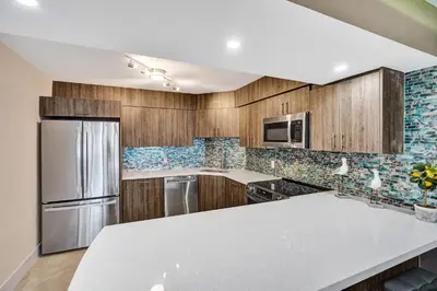 a kitchen with wooden cabinets and stainless steel appliances at Beachside Condo with Resort Amenities, Including Pools, Gym, and Bathtub 503 in Miami Beach