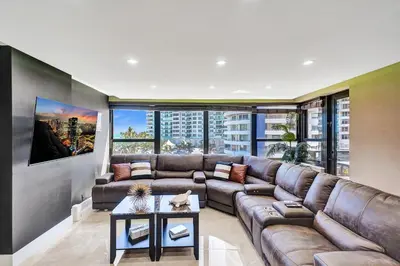 a living room with a brown couch and a large window at Beachside Condo with Resort Amenities, Including Pools, Gym, and Bathtub 503 in Miami Beach