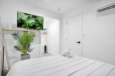 a white bedroom with a tv on the wall at Tropical Guest House at VIlla Verde Miami in Miami