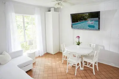 a white dining room with a table and a tv at Miami Pool Cottage in Miami