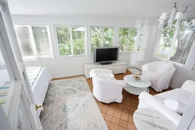 a living room with white furniture and a flat screen tv at Miami Pool Cottage in Miami