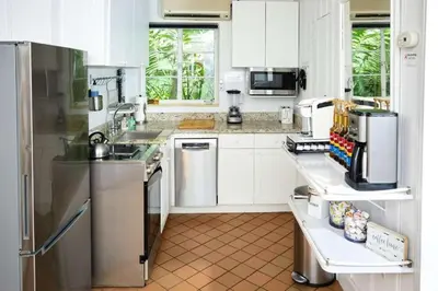 a kitchen with white cabinets and stainless steel appliances at Miami Pool Cottage in Miami
