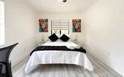 a white bedroom with a large bed with black pillows at Little Havana Paradise in Miami