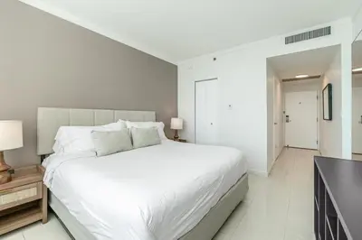 a white bedroom with a large bed and a sink at 2 bedroom Bay View Beauty in Coconut Grove- Parking for 2 cars included! in Miami