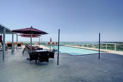 a pool with a table and chairs and an umbrella at Bay View Beauty 1 Bedroom condo in Coconut Grove Parking Included in Miami