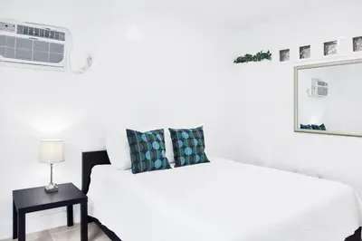 a white bedroom with a white bed and a night stand at Miami Designer Apartment Unit 1 in Miami