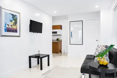 a living room with a black couch and a tv at Miami Designer Apartment Unit 1 in Miami
