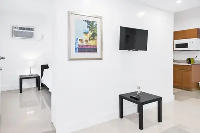 a white room with a table and a tv on a wall at Miami Designer Apartment Unit 1 in Miami