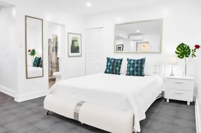 a white bedroom with a large bed and a mirror at Miami Designer Apartment Unit 3 in Miami