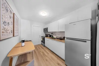 a white kitchen with a table and a refrigerator at Chic 1-BD Apt in Miami Gym, BBQ, Free Parking in Miami