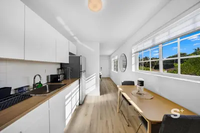 a kitchen with white cabinets and a wooden table at Miami Retreat - 1-BR Parking, Gym & BBQ Area in Miami