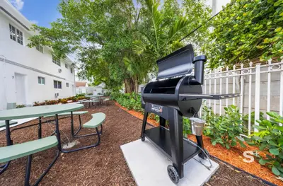 a bbq grill and picnic tables in a courtyard at Modern 1-BD Miami Apt Gym, BBQ, Free Parking in Miami