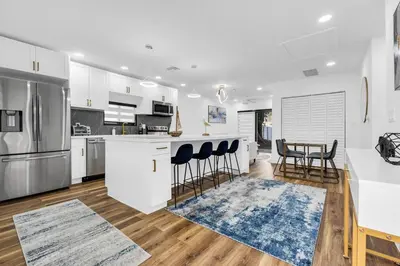 a kitchen with white cabinets and a table and chairs at Modern Home with large private yard - Next to downtown & beach & airport - Pet friendly in Fort Lauderdale