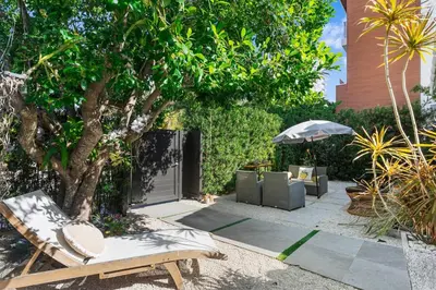 a patio with a tree and a chair and an umbrella at Stunning, Modern and Quiet Beach House in Hollywood