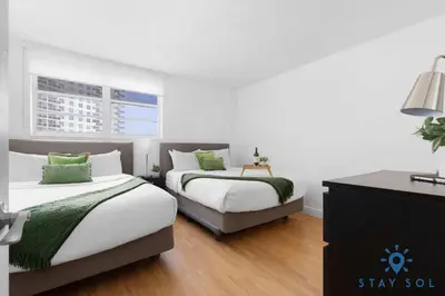two beds in a room with white walls and wood floors at Tides beautiful ocean view condo-promotions in Hollywood