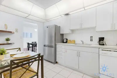 a white kitchen with a table and a refrigerator at Tides Great condo on the beach Big promotions in Hollywood
