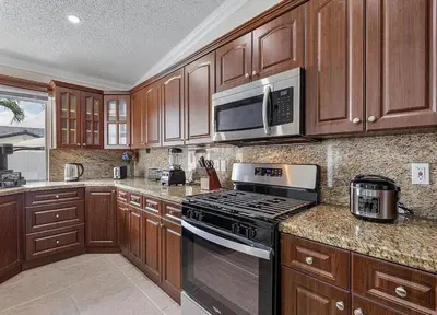 a kitchen with wooden cabinets and a stove and microwave at Miami Oasis With Private Pool in Richmond West