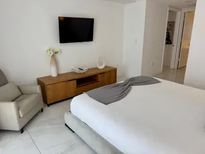 a bedroom with a bed and a tv and a chair at Hallandale Beach Apmt 1B1B with Beach Service & Pool Service in Hallandale Beach