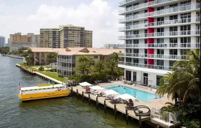 a yellow boat on a river next to a large building at Beach Apt Full kitchen and King size bed in Hallandale Beach