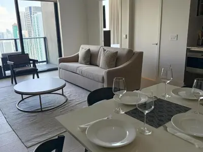 a living room with a couch and tables with wine glasses at Sky-High Views Pool – Steps from Miami Arena in Miami