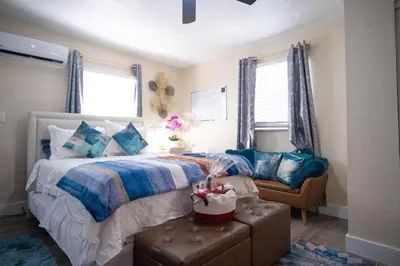 a bedroom with a bed with blue pillows and a chair at Hidden Gem Luxe 1 BEDROOM & Patio in Cutler Bay