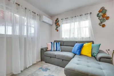 a living room with a gray couch with colorful pillows at 2 Mi to Hard Rock Stadium Studio in Miami Gardens in Miami