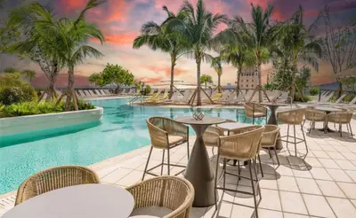 a resort pool with tables and chairs and palm trees at Modern Stylish 1BR Apartment with Pool in Miami