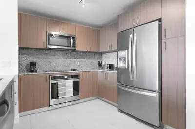 a kitchen with wooden cabinets and a stainless steel refrigerator at Beautiful and Stylish Condo Close The Doral Park in Miami
