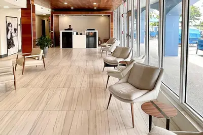a waiting room with chairs and tables and windows at Solara Surfside in Miami Beach