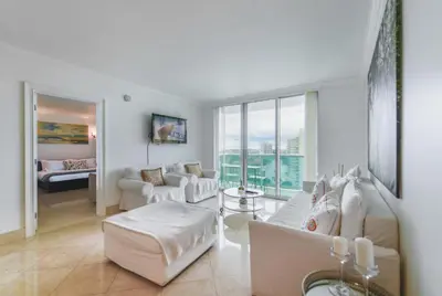a living room with white furniture and a large window at Hollywood Beachfront Retreat in Hollywood