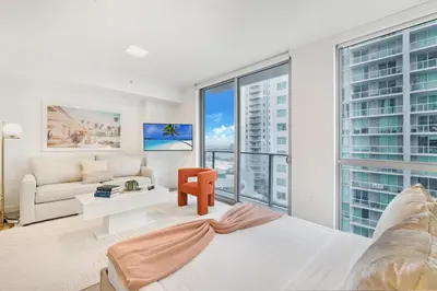 a living room with a large bed and a couch at Designer Studio Downtown Miami with Rooftop Pool and Gym in Miami