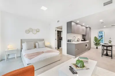 a white bedroom with a bed and a kitchen at Designer Studio Downtown Miami with Rooftop Pool and Gym in Miami
