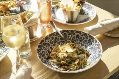 a table with plates of pasta and a glass of wine at Designer Studio Downtown Miami with Rooftop Pool and Gym in Miami